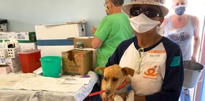 Masked person holding a puppy at a clinic for vet care for the Navajo Nation