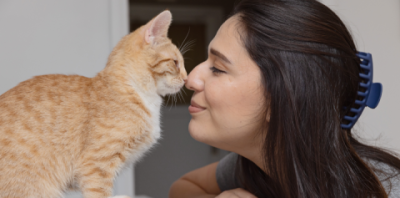 woman kissing an orange kitten