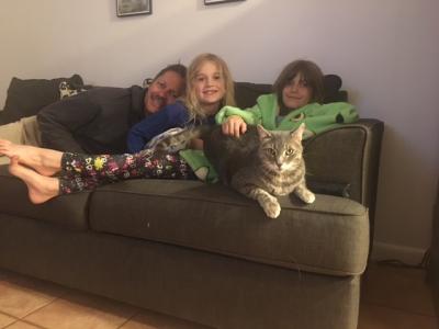 The Williams family on a couch with their sleepover cat
