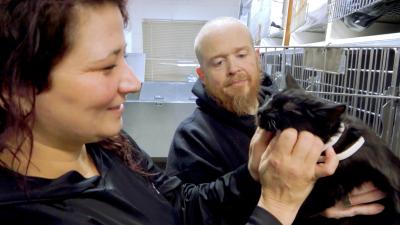 Two people from Harrison County Animal Control with a black cat