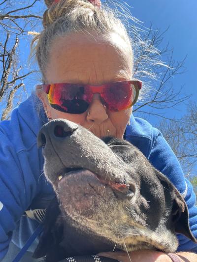 Melissa “Missy” Kidwell wearing sunglasses with a dog in front of her