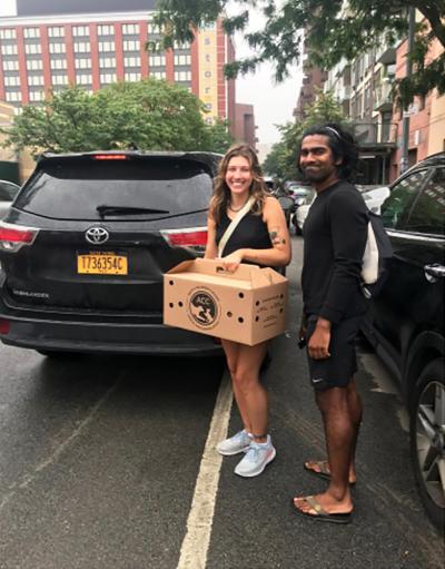 Two people holding a carrier next to a Lyft vehicle