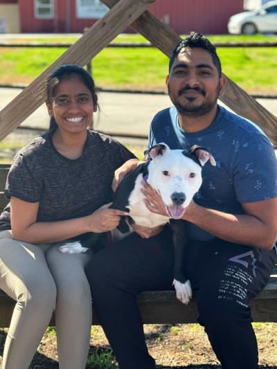 Couple sitting together with a black and white dog they adopted