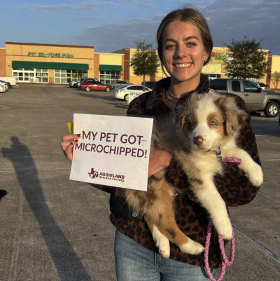 Person holding a puppy and a sign that says, "My pet got microchipped"