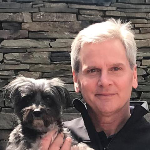 Steve Howell holding small black fluffy dog
