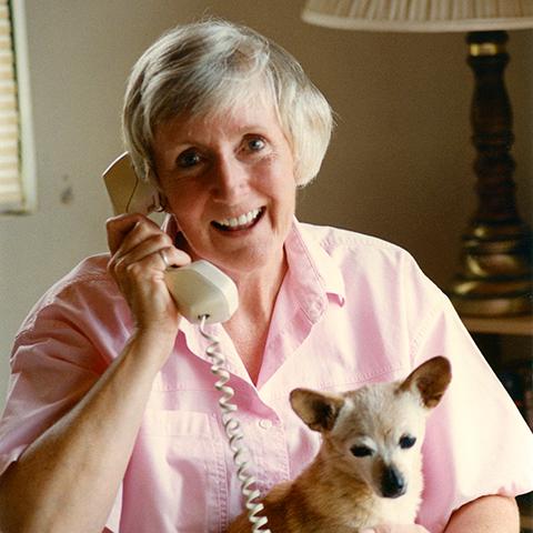 Charity Rennie on the phone holding a small dog