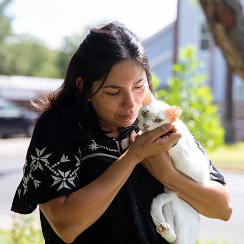 Woman cradling a white cat with an ear-tip in her arms