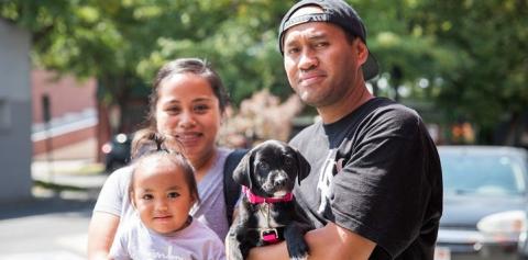 Couple with small child with man holding black and white puppy