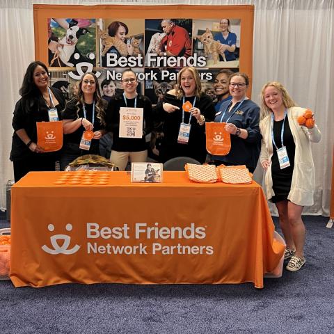 Best Friends Network Partner booth at a conference with the team holding up conference swag