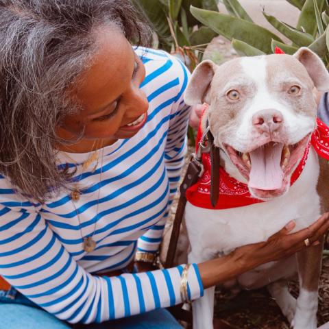 Older woman sitting with smiling dog in red bandana