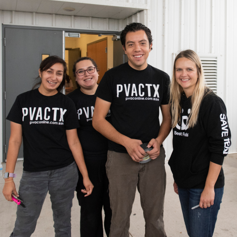 Three women and one man posting for a group photo in shirts for PVACTX