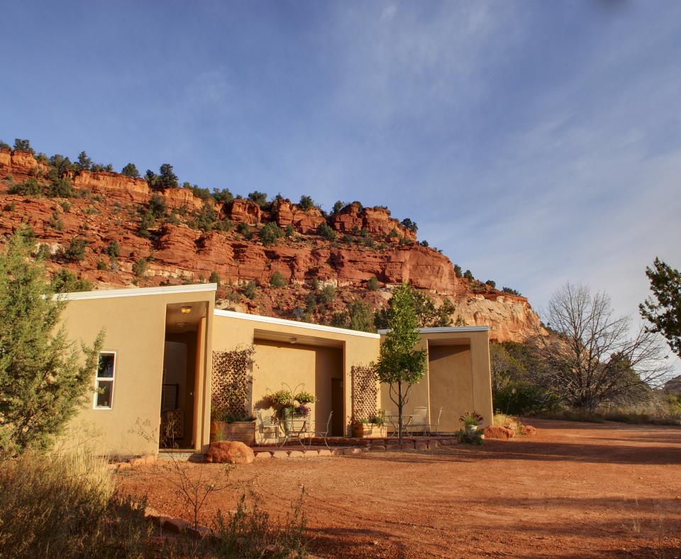 Small tan building with a backdrop of red rock cliffs and blue sky