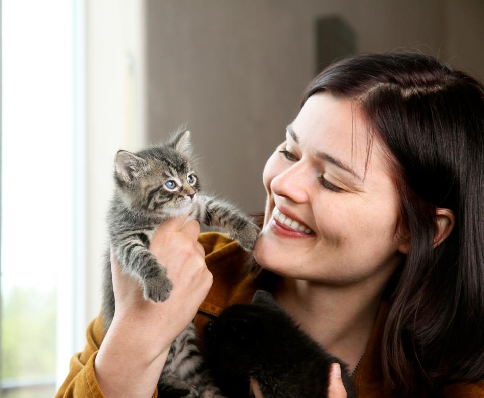 Smiling person holding a tabby kitten
