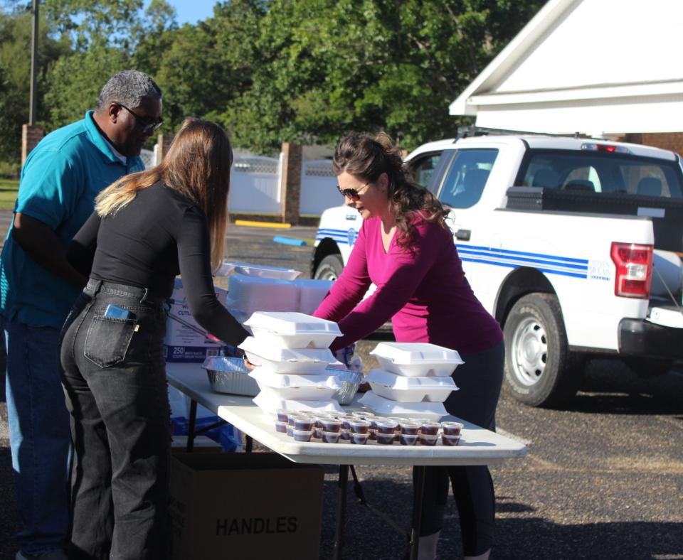 People next to a table full of styrofoam containers containing food from the Pancakes and Puppies fundraiser