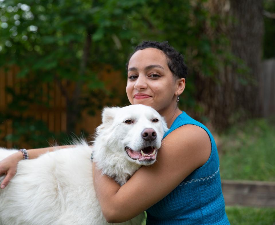 Smiling person hugging a large white dog outside in a fenced area