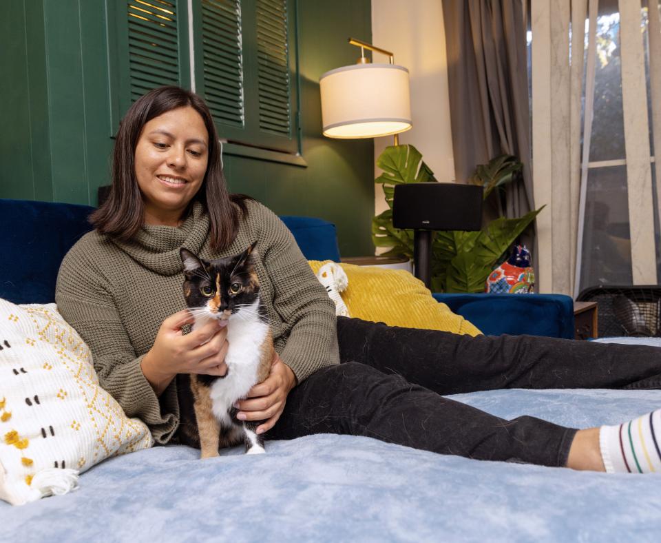 Smiling person relaxing on a bed with a cat