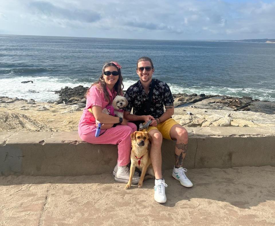 Bagel the dog on a beach with his two people and another dog