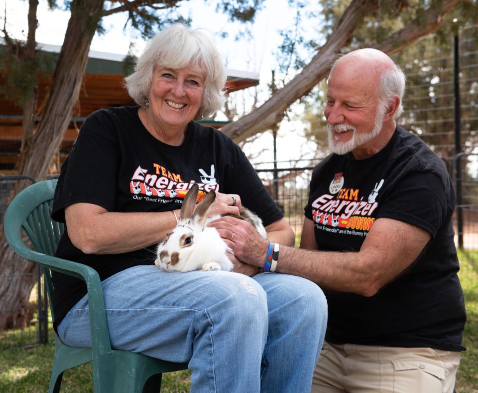 Two smiling people sitting with a bunny outside