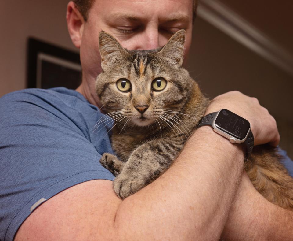 Man hugging a tabby cat
