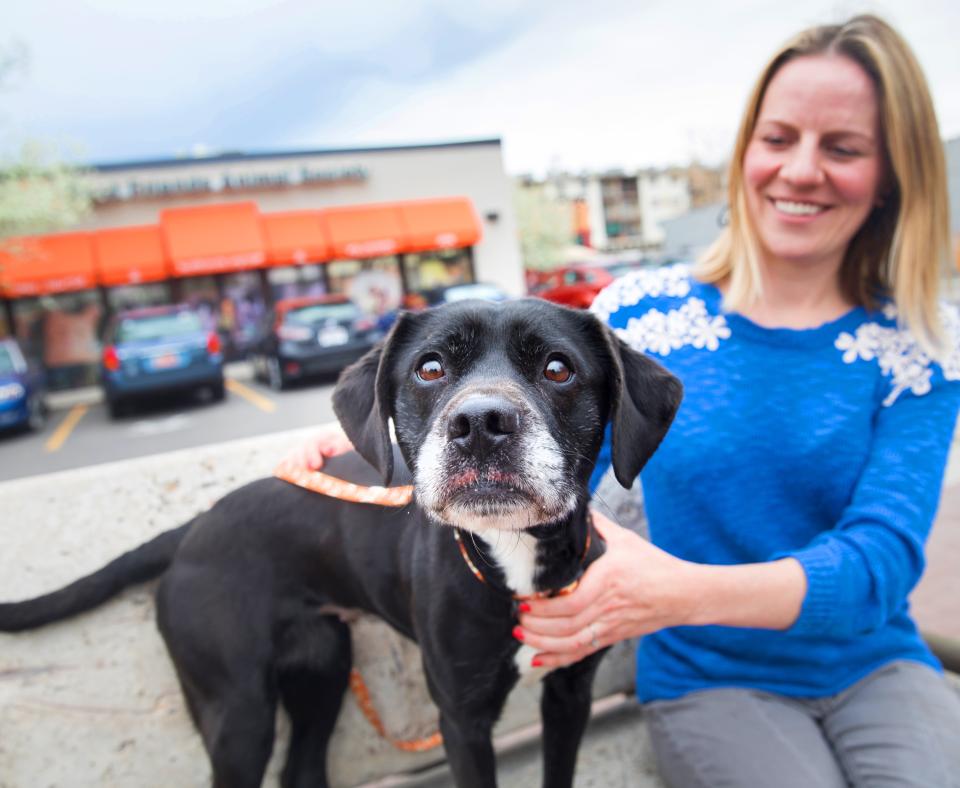 Smiling person sitting in front of Best Friends Pet Adoption Center in Salt Lake City with a dog