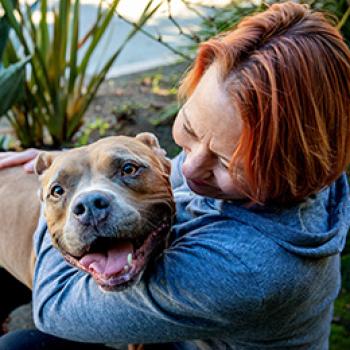 Woman hugging happy pit bull dog