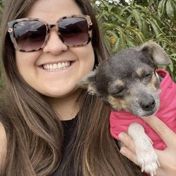Smiling person holding a small dog