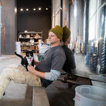 Person sitting with a cat in a Salt Lake City distillery