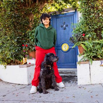 Person and black dog standing outside a residence with a blue door