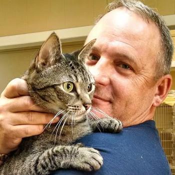 John Ballard holding brown tabby cat close to face
