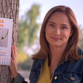 Smiling person standing next to a flyer posted on a tree