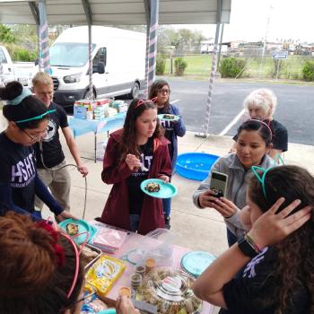 Group of people outside at a kitten shower celebrating, some wearing cat ears and eating cake