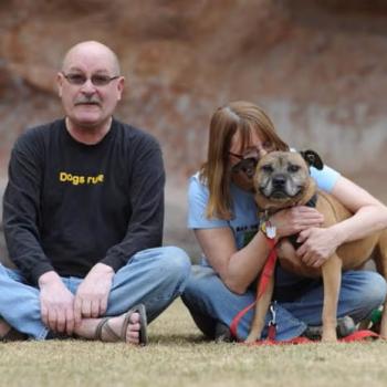 Couple sitting in grass with Ray the Vicktory dog