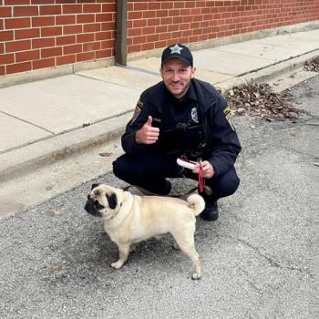 Community service officer Sean Bus giving a thumbs up sign with Wilson the pug 