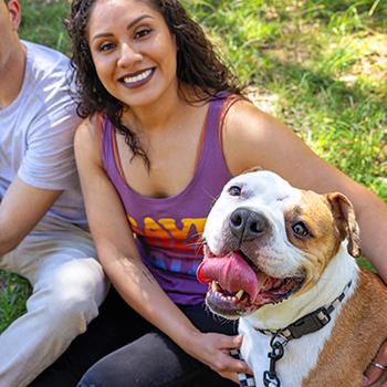Smiling person wearing a Save Them All Best Friends tank top with arms around a happy dog