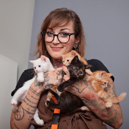 Smiling woman holding a bunch of kittens
