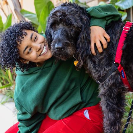 Smiling person hugging a big dog outside