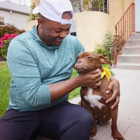 Smiling person sitting with a dog outside on some steps