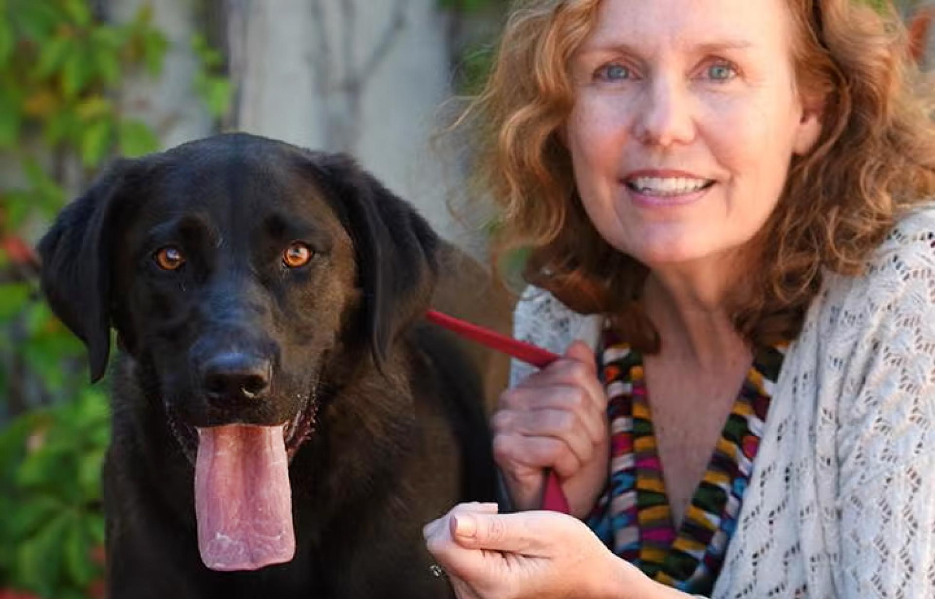 Abby Jones beside a black dog whose tongue is out