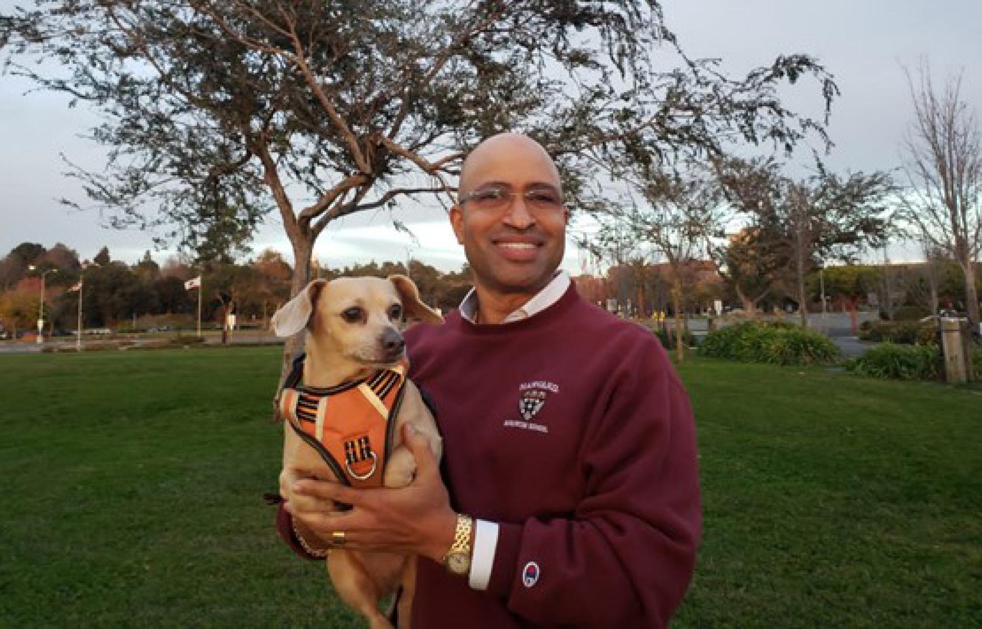 Joe Angelo holding a small brown Chihuahua-type dog