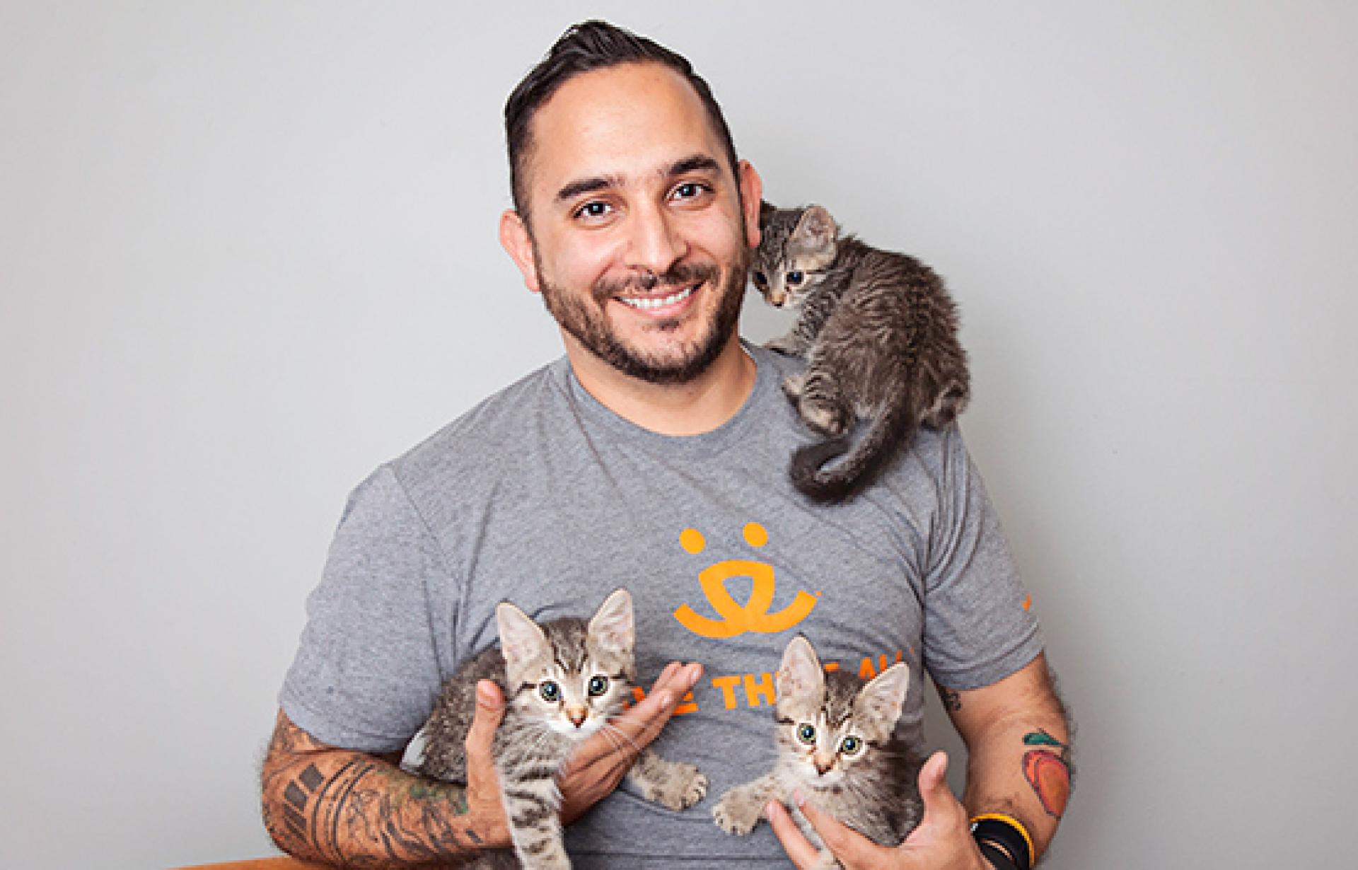 Marc Peralta holding three kittens, including one on his shoulder
