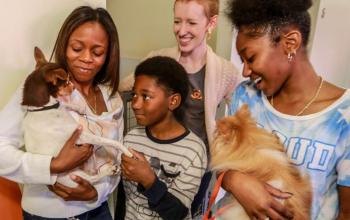A family of three and an adoption counselor hold two dogs at the Best Friends Lifesaving Center in Atlanta