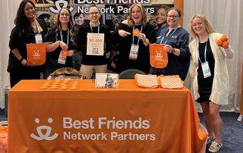 Best Friends Network Partner booth at a conference with the team holding up conference swag