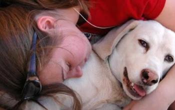 Person lying down and hugging a white dog