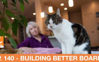 A cat on a table with a woman in the background