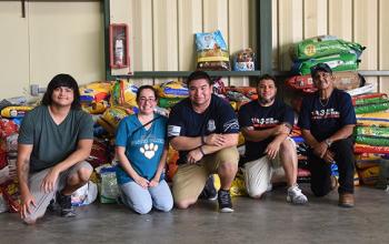 Group of people sitting in front of a large pile of donated items
