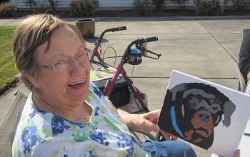Woman showing off painting of black and brown dog
