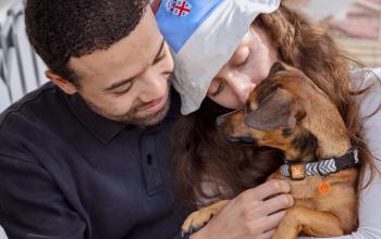 Man and woman cuddling with foster dog