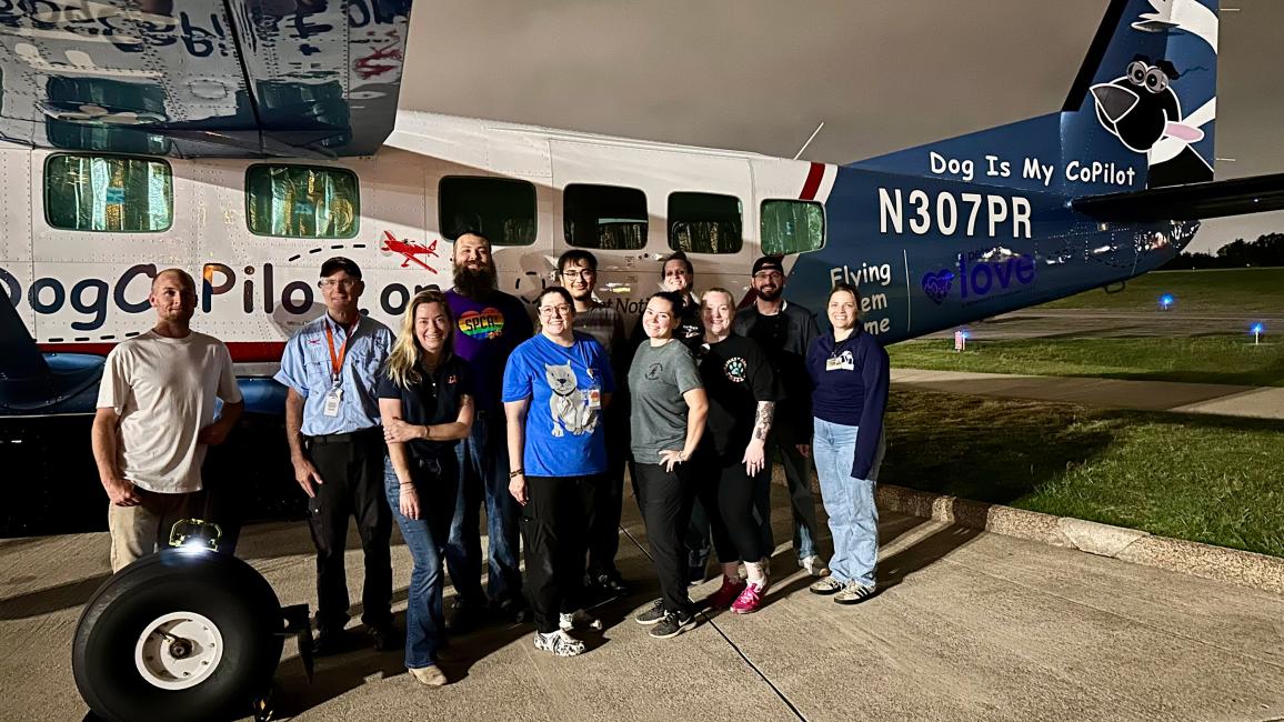 Group of people beside a Dog is My Co-Pilot plane