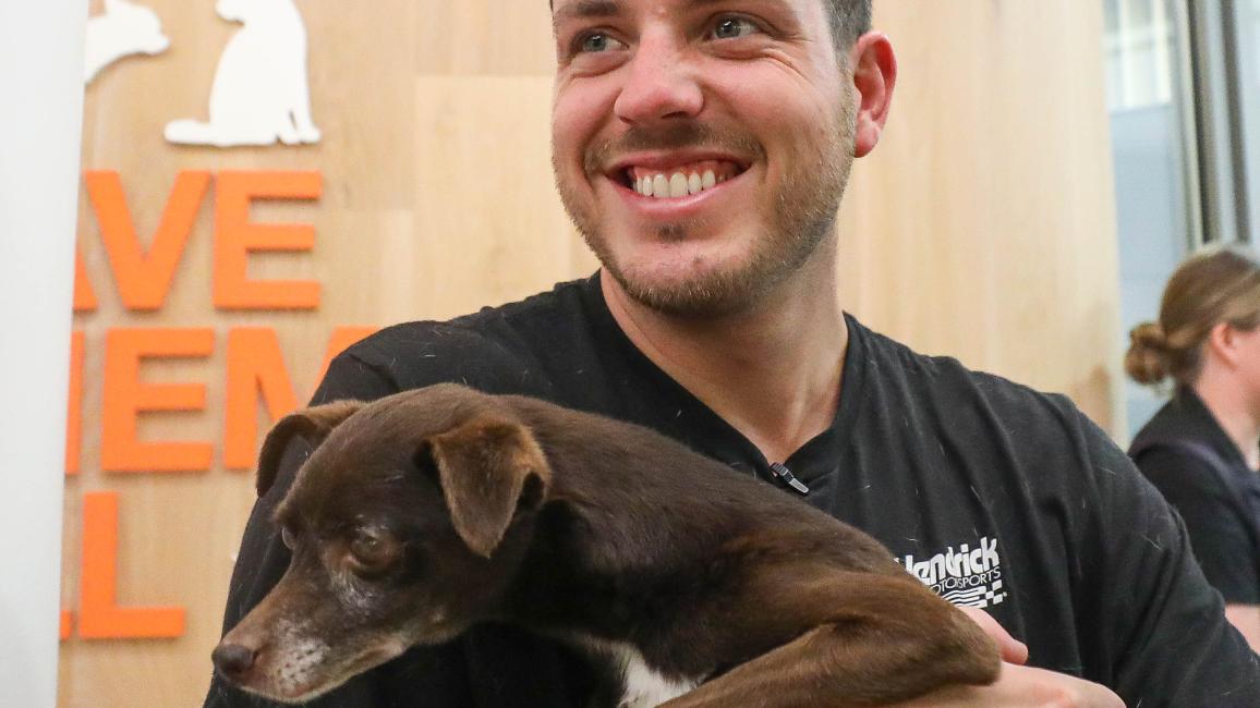 Alex Bowman smiling and holding a small dog