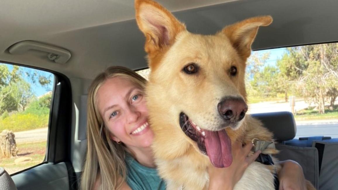Emma hugging Archie the dog  in the back seat of a vehicle